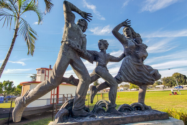 A statue depicts a woman holding a baby, a school aged child and a man running from a hurricane.