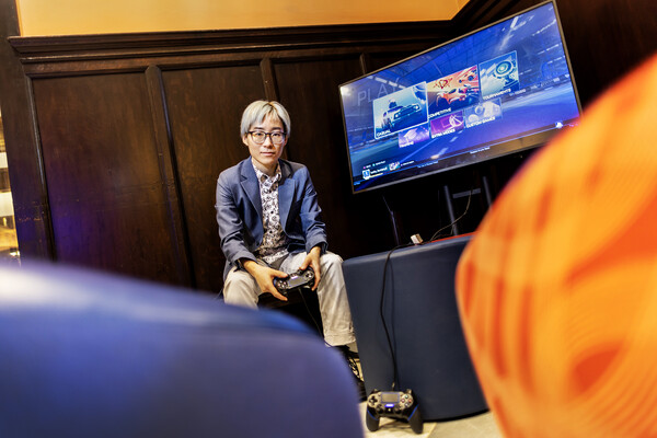Bean bag chairs in foreground and Mengyang Zhao in background with a video game controller