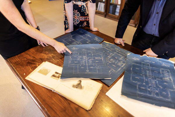 four blueprint architectural drawings on a table with an open photo book