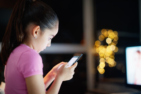 A child uses a cell phone in a dark room