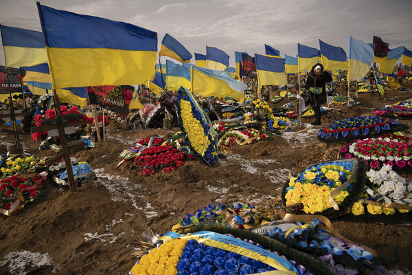 A graveyard is covered in Ukrainian flags and large displays of flowers.