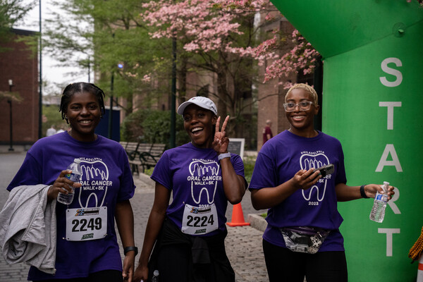 Three people participate in an organized run and walk, wearing matching t-shirts