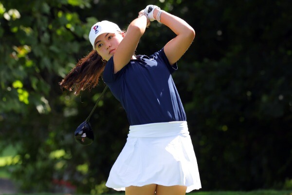 First-year Bridget O’Keefe holds up golf club behind her head after finishing a swing.