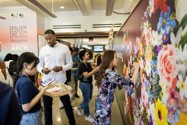 Will Atkins, Vicky Aquino, and students affix flower stickers to the new AAPI mural