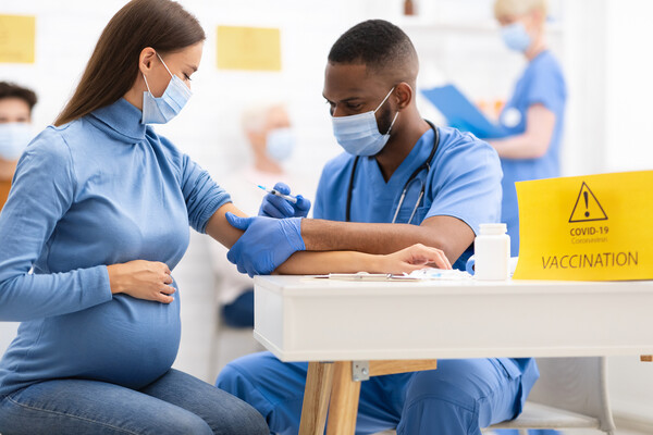 A pregnant person receives a COVID vaccine.