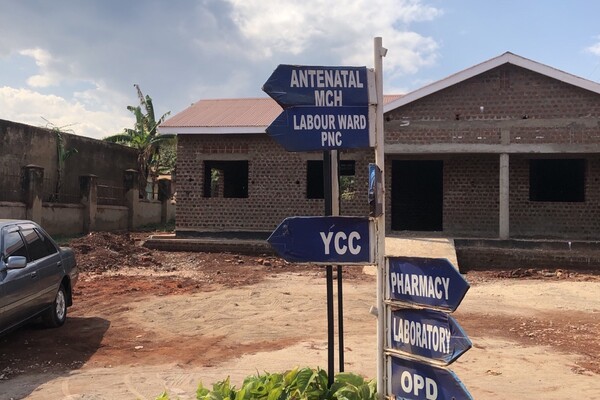 Image of a brick building with signs out front pointing to "Antenatal MCH, Labour ward PNC, YCC, Pharmacy, Laboratory, OPD"