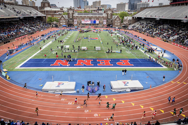 At Franklin Field, athletes take part in the Penn Relays while spectators watch from the stands.