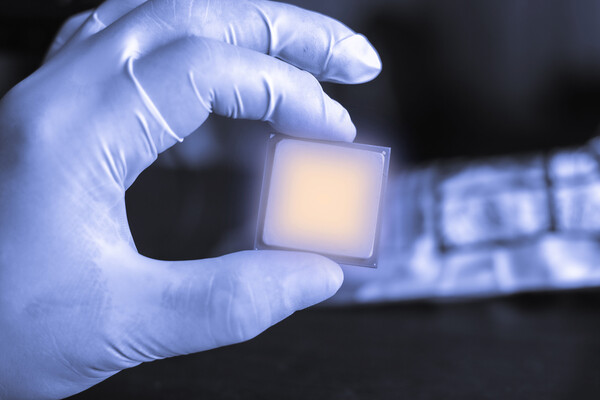 Gloved hand holding a photonic chip.