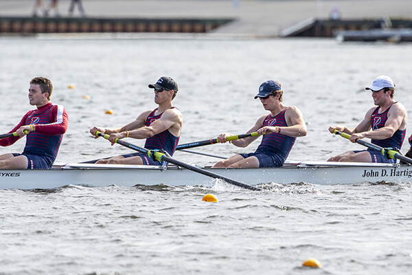 Members of the heavyweight rowing team row in a boat on the water.
