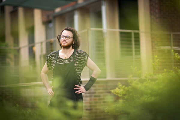 Nathan Nyitrai stands with hands on hips in the garden in front of the SP2 building 