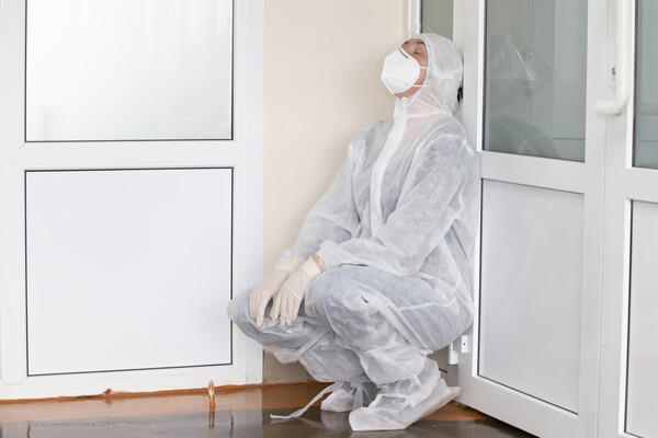 An ER doctor in full PPE rests on the floor alone.
