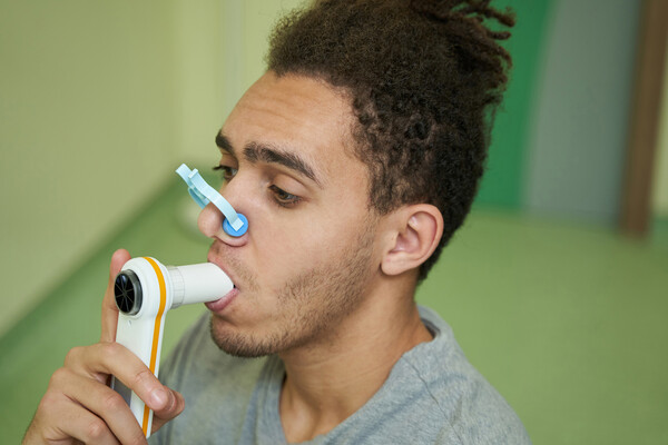 An African American person using a spirometer.