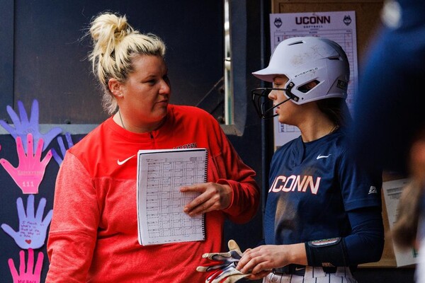 While coaching at UConn, Christie Novatin speaks with one of her players in the dugout.