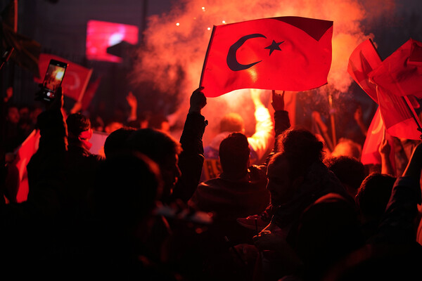 Supporters of Turkish President Erdogan wave Turkish flags in the street at night after his runoff win.