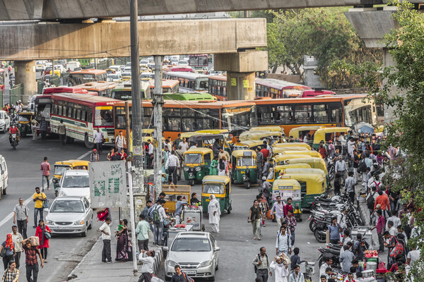 Traffic in New Delhi with pedestrians, buses, and tuktuks.
