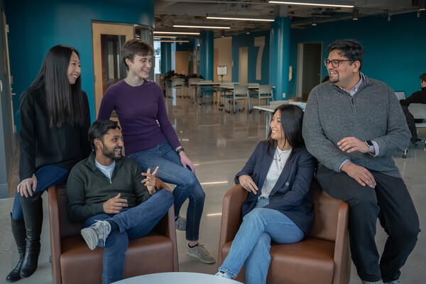 Five people engaged in conversation seated in a lounge.