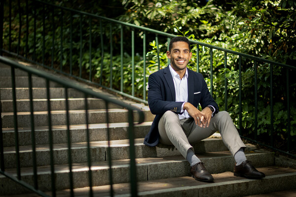 Rich Lizardo sits on concrete stairs in front of greenery on Penn campus.