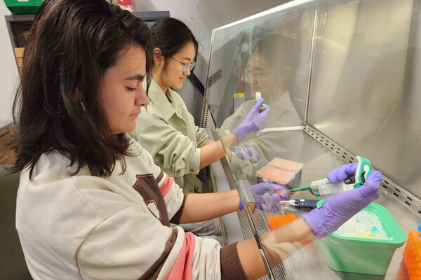Camila Irabien and Dionne Yeung working in a lab side-by-side.
