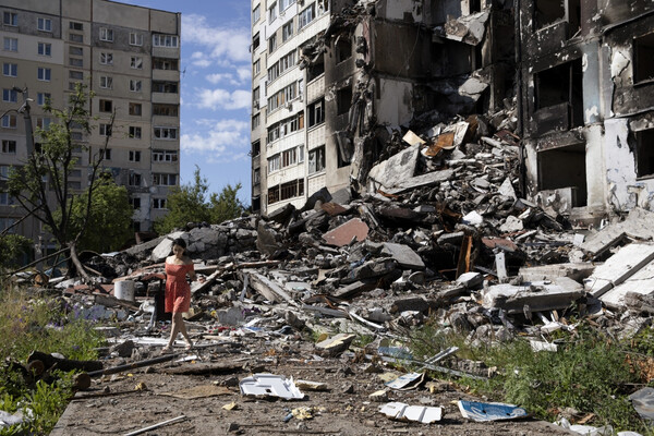 A person walking through the rubble of a collapsed building in Ukraine.