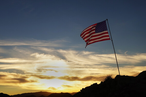 An American flag on a hilltop at dusk.