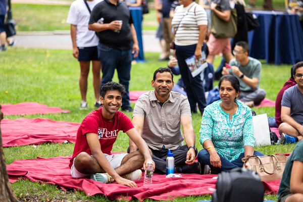 Students and families sitting on tablecloths on College Green.