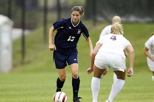 Katy Cross dribbles the ball past a defender during a game.