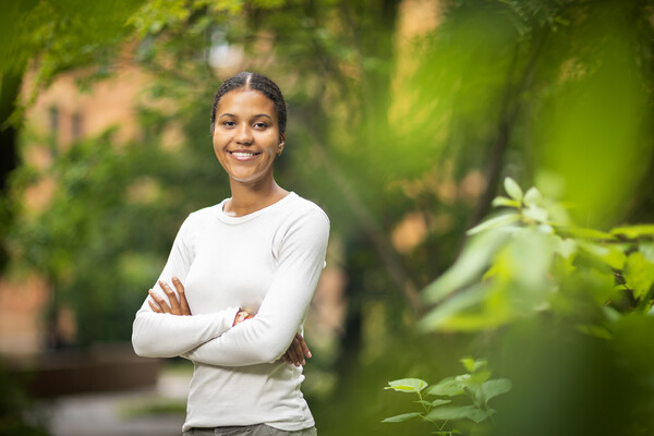 Penn rising fourth-year Sophie Mwaisela stands in front of a brick archway with her arms crossed.