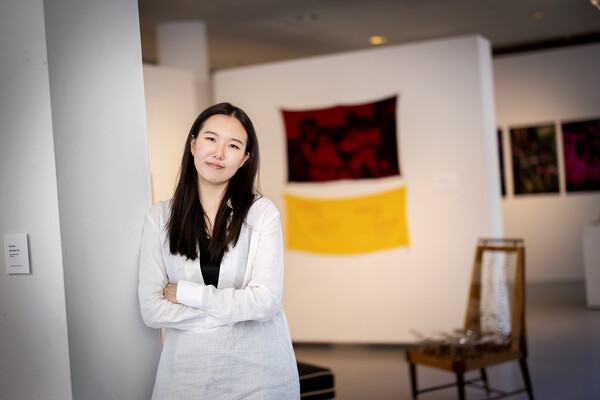 Kay Seohyung Lee standing in art gallery leaning against a wall
