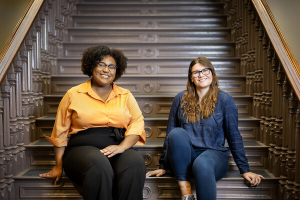 Teia Hudson and Miraya Gesheva sit on steps.