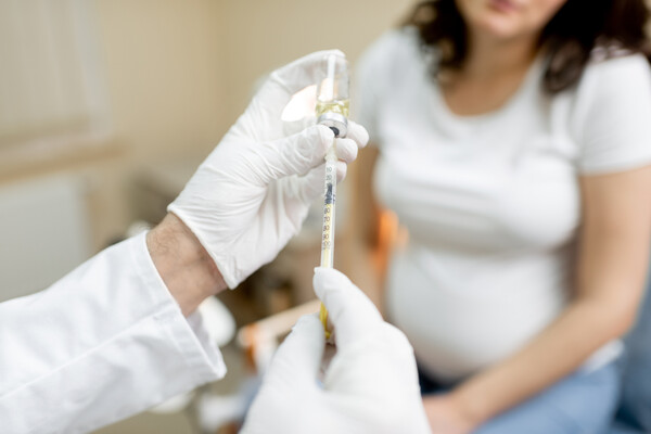 A doctor prepping a vaccine for a pregnant person.