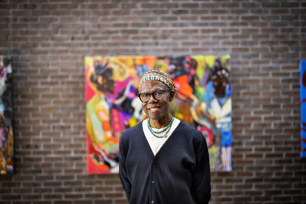 Mikel Elam poses in front of artwork.