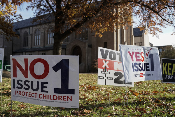 Signs for and against Ohio's Issue 1 are in a lawn covered in fall leaves in front of a church