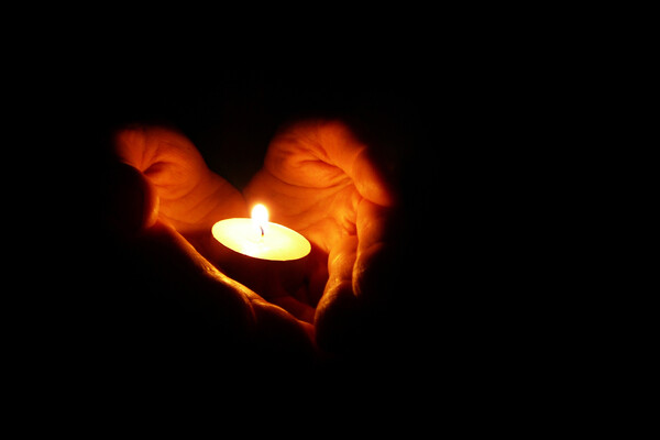 Cupped hands holding a tea light candle.