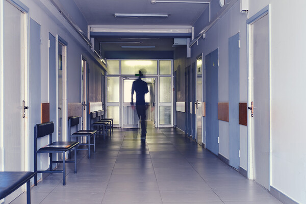 A person leaving the hospital at the end of a long corridor.