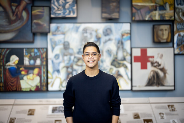 Andre Rosario stands in front of artwork at Penn's School of Nursing.