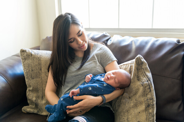 A postpartum person and their newborn on a couch.