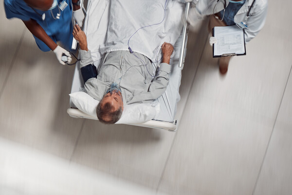A patient being wheeled in the hospital flanked by two medical professionals.