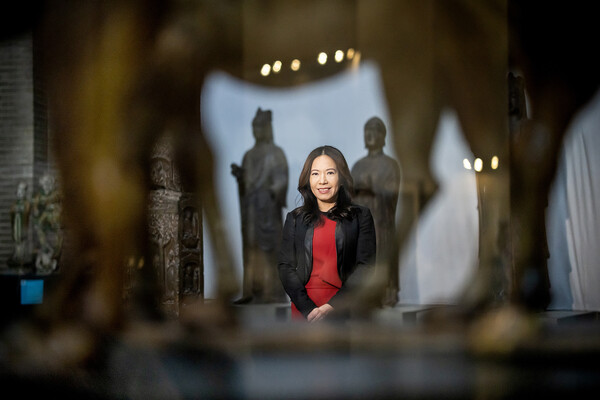 Jo Perez smiles and poses in Asia Gallery in museum. 