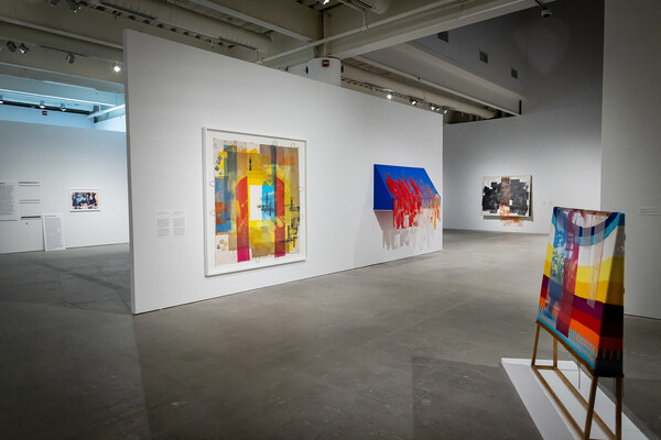 Vibrantly colored paintings on display in a gallery. 