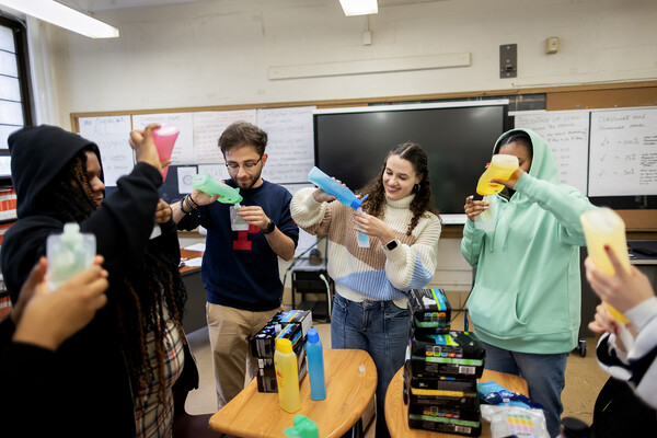 high School and college students pour decant colorful bottles of shampoo and shower gel to make hygiene kits for students