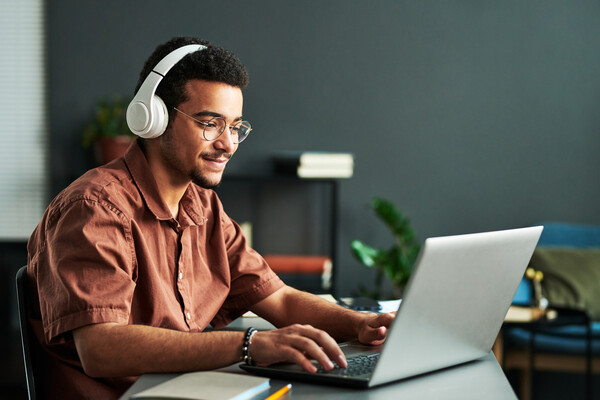 Person working at laptop with headphones on. 