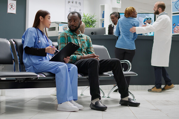 A medical professional talking with someone waiting in an emergency department waiting room.