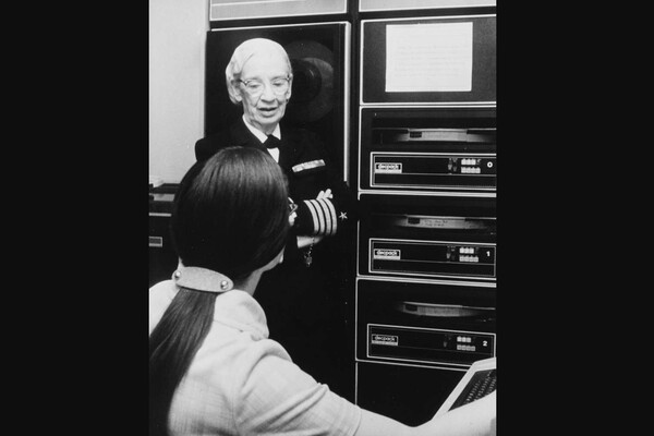 Grace Hopper in Naval gear introducing a computer system to a student.
