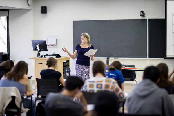 Jennifer Egan standing in front of class gesturing with one hand and holding papers in the other