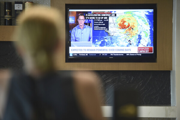 A person watching a news channel showing a weather map.