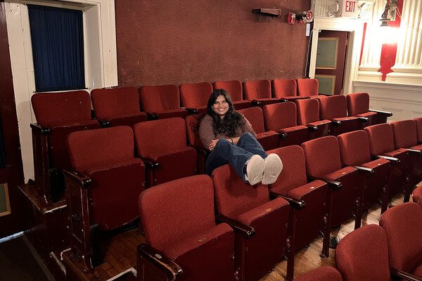 A Penn intern at 1812 seated in the audience seats of a theater.