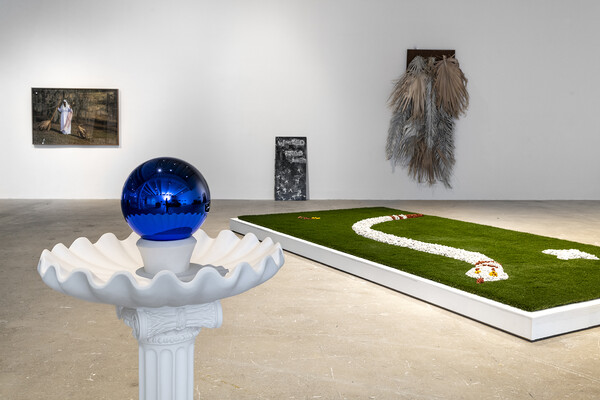 A gazing ball atop a bird bath and a stylized snake on astroturf.