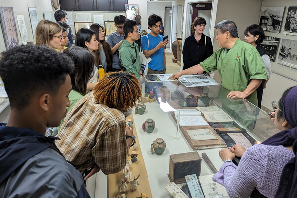 A group of Penn students looking at Japanese artifacts being presented in a museum.