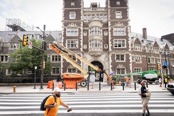 Quadrangle building exterior with cranes outside of it.