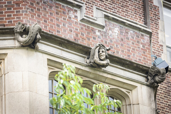 A trio of stone grotesques on the exterior of a building. 